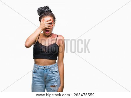 Young braided hair african american with pigmentation blemish birth mark over isolated background peeking in shock covering face and eyes with hand, looking through fingers with embarrassed expression