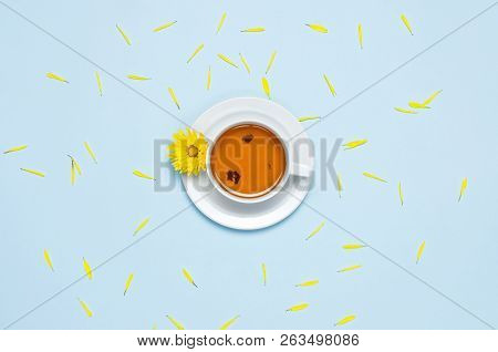 Cup Of Herbal Tea With A Yellow Chrysanthemum On Blue Background Top View Flat Lay. Concept Good Mor