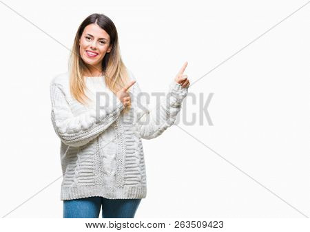 Young beautiful woman casual white sweater over isolated background smiling and looking at the camera pointing with two hands and fingers to the side.