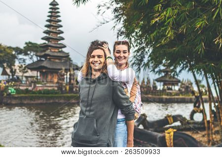 Young Romantic Couple Of Trourists On The Ulan Danu Temple Background. Bali Island.