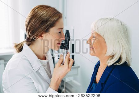 Doctor Optometrist Examining Senior Womans Eye In Doctors Office