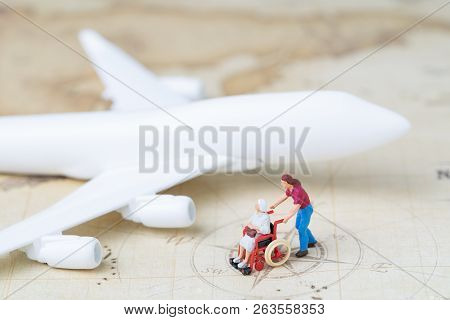 Medical Trip Planning Or Travel Concept, Miniature Senior Elderly People On Wheelchair With Son Or C