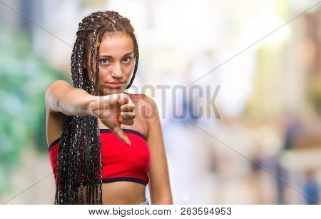 Young braided hair african american with pigmentation blemish birth mark over isolated background looking unhappy and angry showing rejection and negative with thumbs down gesture. Bad expression.