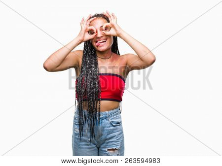 Young braided hair african american with pigmentation blemish birth mark over isolated background doing ok gesture like binoculars sticking tongue out, eyes looking through fingers. Crazy expression.