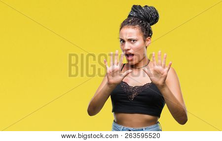 Young braided hair african american with pigmentation blemish birth mark over isolated background afraid and terrified with fear expression stop gesture with hands, shouting in shock. Panic concept.