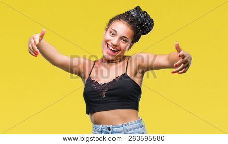 Young braided hair african american with pigmentation blemish birth mark over isolated background looking at the camera smiling with open arms for hug. Cheerful expression embracing happiness.