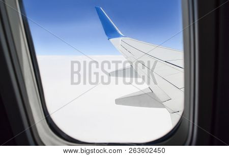 View From Porthole On The Wing And The Clouds Under The Wing Of An Airplane