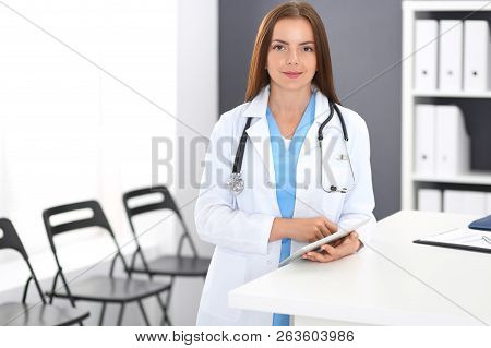 Doctor Woman At Work. Portrait Of Female Physician Using Digital Tablet  While Standing Near Recepti