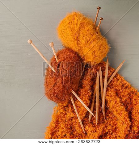 Knitting Yarns And Knitting Needles On Grey Background.