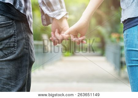 Love And Friendship Concept. Handsome Man And Young Woman Hold On To Little Fingers In Public Park B
