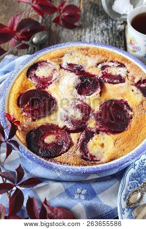 Autumn Dessert. Red Plums Clafoutis And Cup Of Coffee, Icing Sugar Dressing, French Cuisine