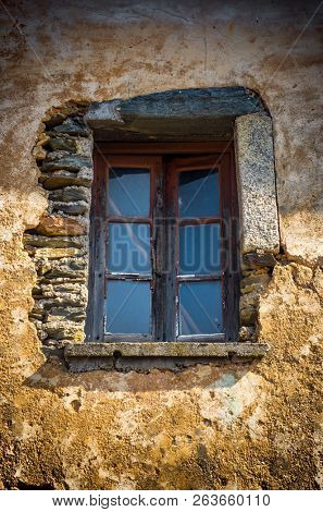 Window centered on a damaged wall of a ruined house