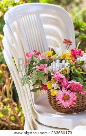 Basket of flowers on a pile of white plastic chairs