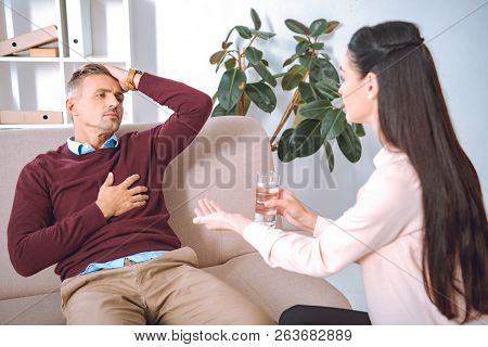 Psychotherapist Giving Glass Of Water And Pill To Patient With Heartache