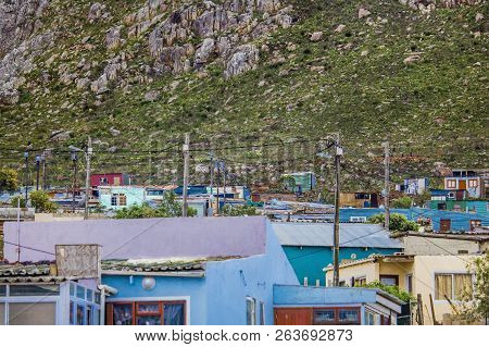 Wide Shot Of Shack Homes In Township Below Massive Mountain In Kleinmond, Western Cape, South Africa