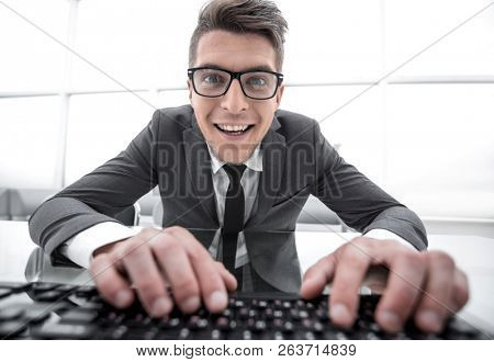 Young man sitting at desk with hands on keyboard and looking clo