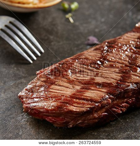 Hot Grilled Whole Denver Steak on Black Stone Background. Fresh Juicy Medium Rare Beef Grillsteak. Barbecue Meat Close Up