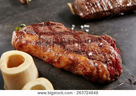 Hot Grilled Whole Tri-tip Steak on Black Stone Background. Fresh Juicy Medium Rare Beef Grillsteak. Barbecue Meat Close Up