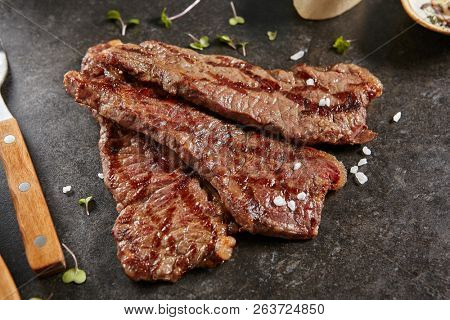Hot Grilled Whole Gaucho Steak on Black Stone Background. Fresh Juicy Medium Rare Beef Grillsteak. Barbecue Meat Top View Close Up