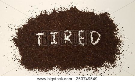 Tired Spelled Out In Ground Coffee/coffee Grinds On White Background