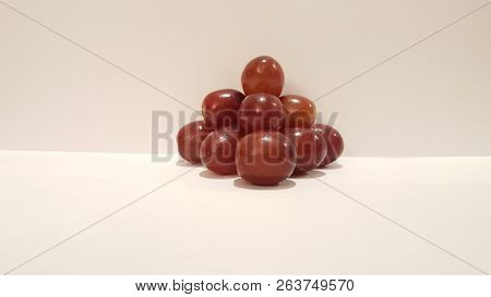 Red Grapes Stacked Into A Pyramid On White Background.