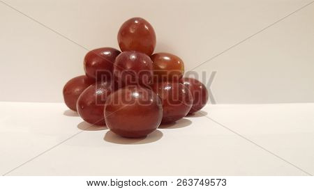 Red Grapes Stacked Into A Pyramid On White Background.