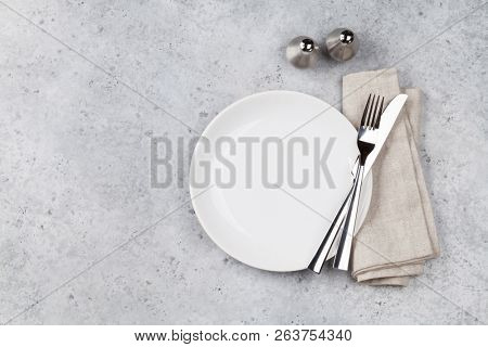 Table setting. Empty plate, knife, fork, spices and napkin. Top view and flat lay with copy space