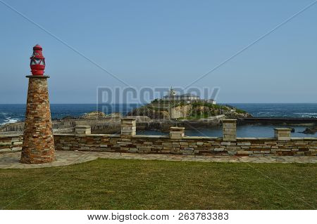Monument With A Lantern With The Lighthouse At The Background In Tapia De Casariego. Nature, Travel,