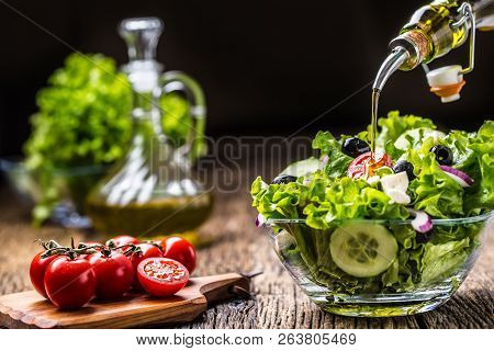 Vegetables Lettuce Salad With Tomatoes Onion Cheese And Olives. Olive Oil Pouring Into Bowl Of Salad