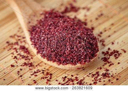 Close Up Of Ground Sumac Spice Powder In Wooden Spoon