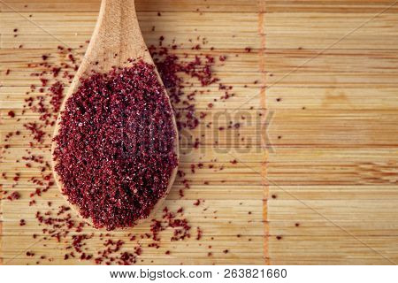 Ground Sumac Spice Powder In Wooden Spoon. Top View With Copy Space