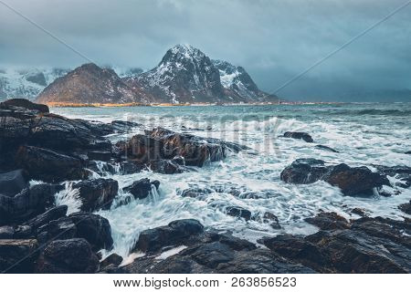 Waves crushing on rocks on rocky coast of fjord of Norwegian sea in winter. Lofoten islands, Norway