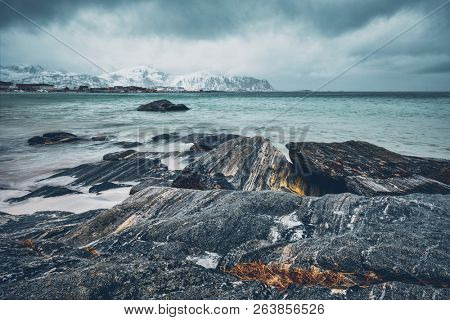 Waves of Norwegian sea on rocky beach of fjord. Ramberg beach, Lofoten islands, Norway