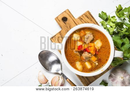 Goulash Soup With Meat And Vegetables On White Stone Table. European Cuisine. Top View With Copy Spa