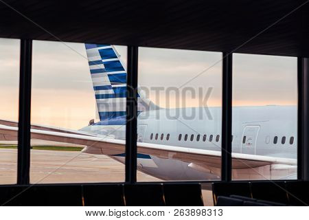 View of airplane fuselage tail through window at airport