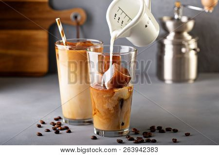 Iced Coffee In Tall Glasses Made With Coffe Ice Cubes With Milk Or Creamer Pouring Over