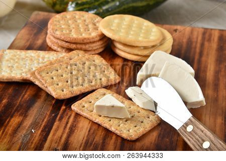 Pepper Jack Cheese Wedges With Gourmet Crackers And A Cheese Knife On A Cutting Board.
