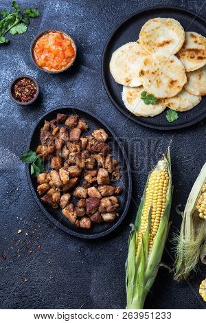 Colombian Food. Maize Arepas And Fried Pork Chicharron Ans Colombian Tomato Sauce. Top View. Black B