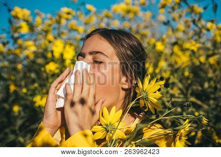 Young Girl Sneezing And Holding Paper Tissue In One Hand And Flower Bouquet In Other. Young Woman Go