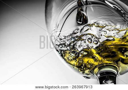 Stream Of White Wine Pouring Into A Glass, White Wine Splash Close-up On A Grey Background. Black An