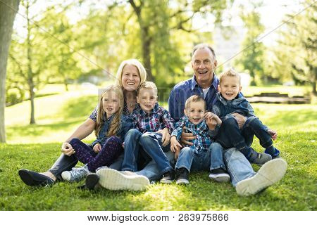 A Senior Person With Littleson On The Grass