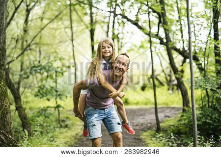 Father Giving His Daughter A Piggyback Ride, Having Fun