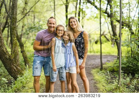 Happy Young Family In Forest Having Fun Together
