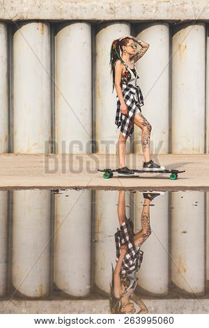 Young Girl With A Longboard On The Background Of Concrete Structure