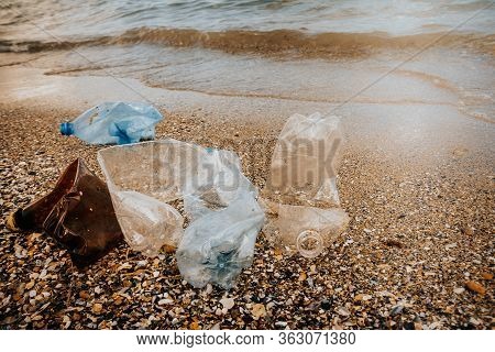 Rubbish Plastic Disposable Bottles  Abandoned On Sandy Beach Around The Sea . Plastic Waste Pollutio