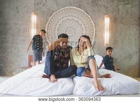 Depressed Tired Asian Parents Tired Of Noisy Active Children Playing At Home. Exhausted Stressed Mal