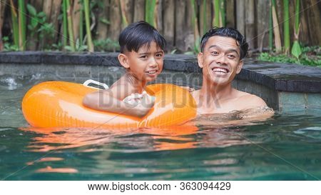 Happy Indonesian Or Malasian Family With Kids Having Fun In Swimming Pool. Smiling Parents And Child