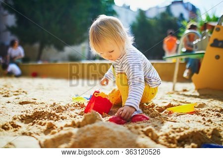 Adorable Little Girl On Playground In Sandpit. Toddler Playing With Sand Molds And Making Mudpies. O