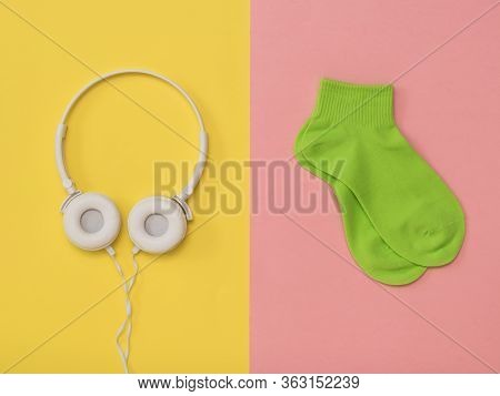 Green Socks And White Headphones With A Wire On A Yellow And Red Background. The Color Trend. The Co