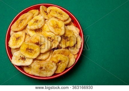 Healthy Sweet Snack, Crispy Dehydrated Unsugared Banana Chips In Bowl On Green Background